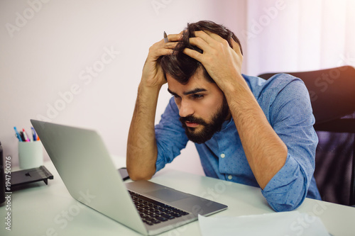 Worried businessman using laptop computer.