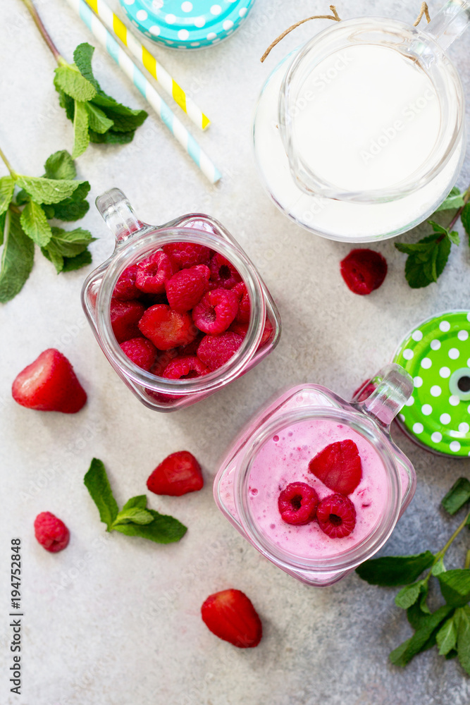 Mason jar mugs with fresh berry cocktails and ingredients for cooking smoothies against a background of gray stone or slate. The concept of proper nutrition and health or detoxification. Copy space. Mason jar mugs with fresh berry cocktails and ingredients for cooking smoothies against a background of gray stone or slate. The concept of proper nutrition and health or detoxification. Copy space.