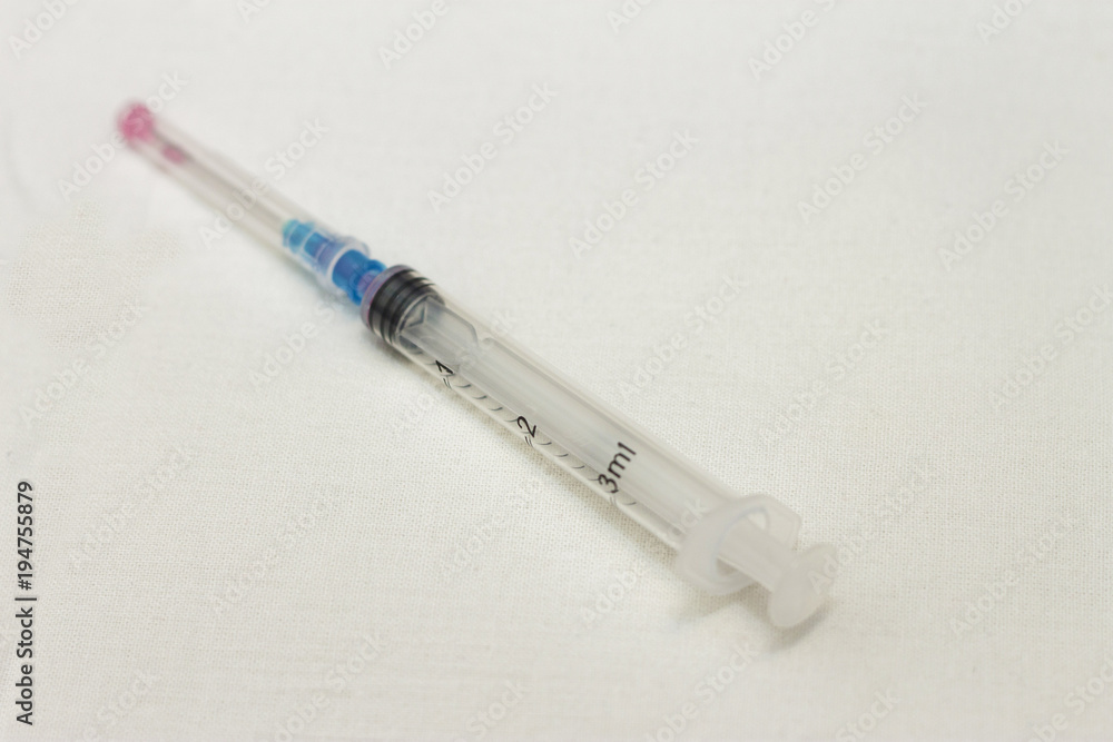 One syringe with cap and needle after using on the white bckground One syringe with cap and needle after using on the white bckground