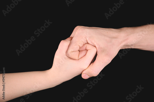 Man and woman holding hands together on black background. Unity concept