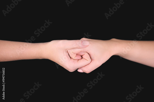 Women holding hands together on black background. Unity concept