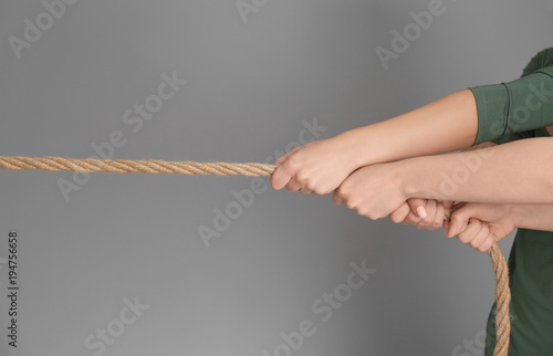 People pulling rope together on grey background. Unity concept