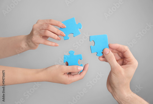 People holding puzzle pieces together on grey background. Unity concept