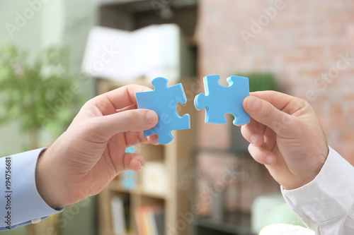 Men holding puzzle pieces on blurred background. Unity concept