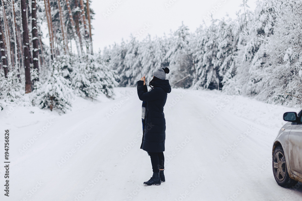 The girl walks and poses on the camera in the background of the winter forest