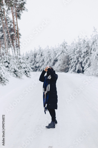 The girl walks and poses on the camera in the background of the winter forest © pressahotkey