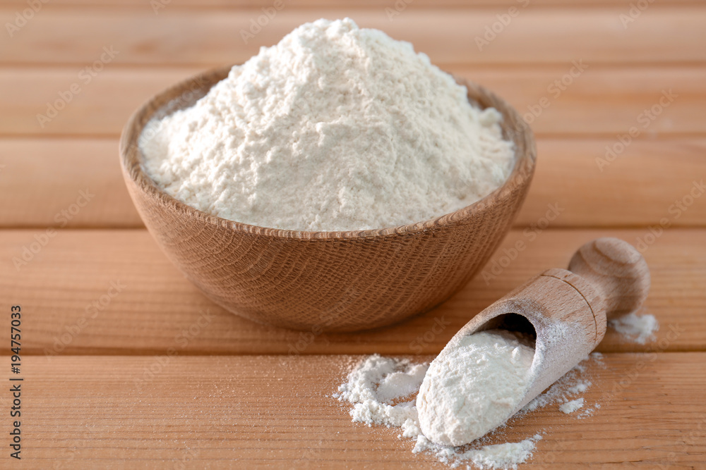 Scoop an bowl of wheat flour on wooden table Scoop an bowl of wheat flour on wooden table