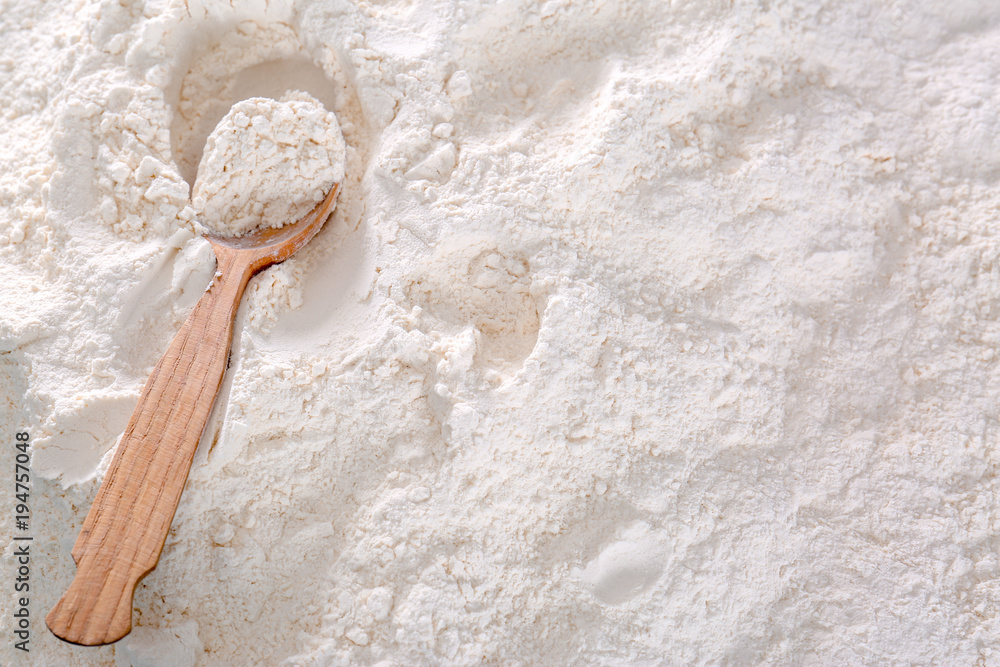 Wheat flour and wooden spoon, closeup Wheat flour and wooden spoon, closeup