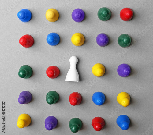 Board game figures and one different on grey background