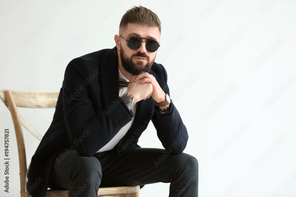 Portrait of handsome hipster in stylish outfit on light background Portrait of handsome hipster in stylish outfit on light background