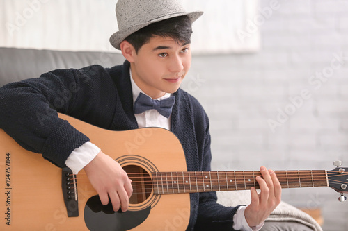 Portrait of handsome hipster with guitar indoors