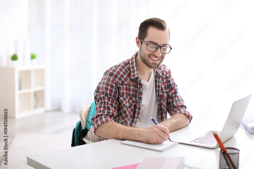 Student with laptop studying at table indoors Student with laptop studying at table indoors