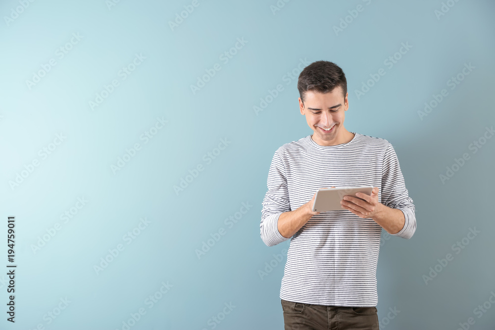 Young man using tablet computer on color background Young man using tablet computer on color background