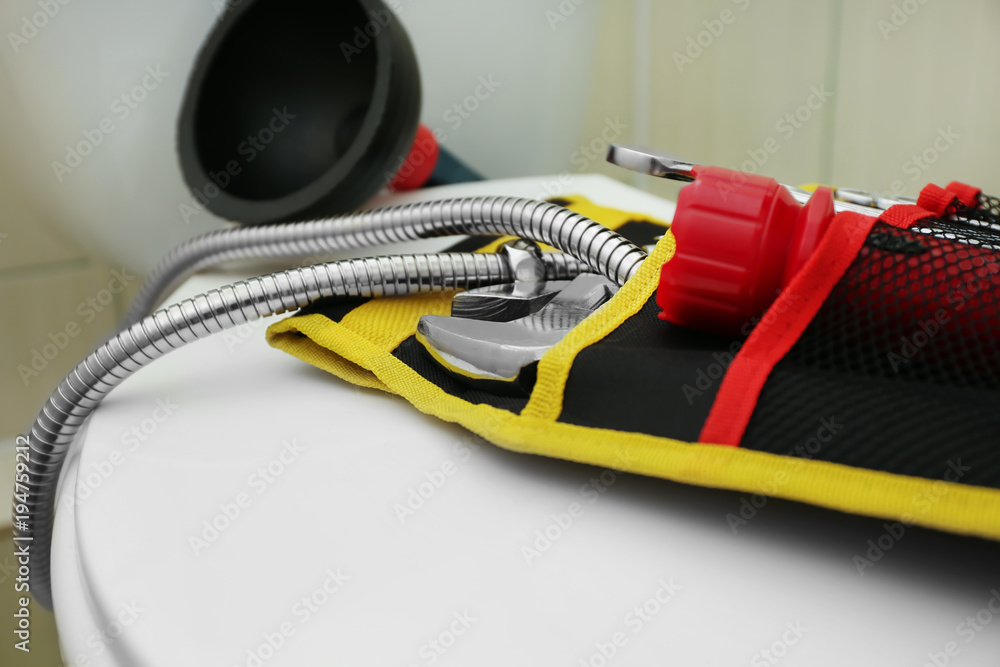 Plumber's tools on toilet seat lid indoors Plumber's tools on toilet seat lid indoors