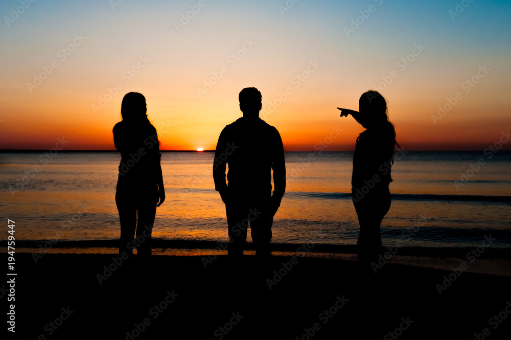 Φωτογραφία Silhouette of three friends in the morning at the beach looking at sunrise