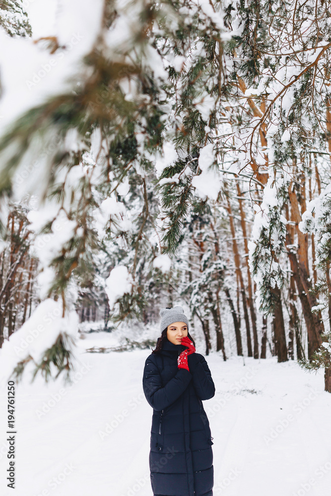 The girl walks in a snow-covered forest among the pines in red gloves The girl walks in a snow-covered forest among the pines in red gloves