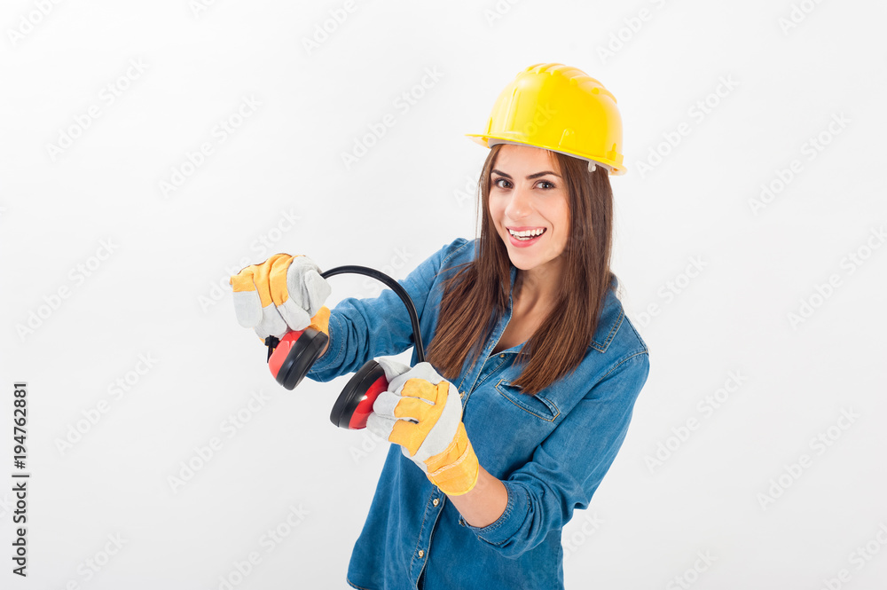 Young woman wearing a yellow hard hat and full protective gear smiling at the camera. Isolated over white background.