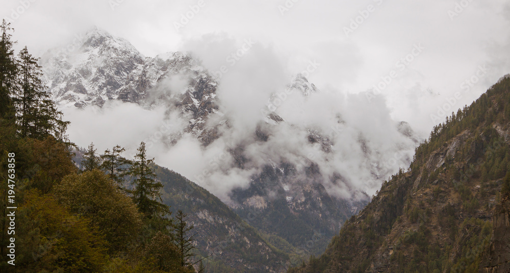 Foggy and cloudy morning mountains in himalayas. Row of mountains with green pine trees.Nepal. nearby Annapurna.