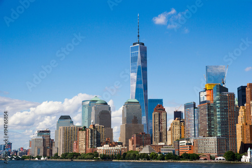 New York’s Manhattan cityscape and famous skyscrapers look striking and colorful reflecting the bright blue late afternoon sky and clouds, as seen from Hudson River