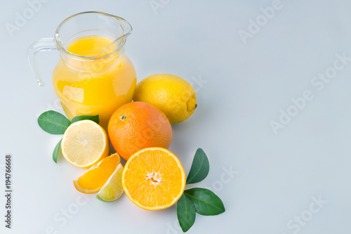 Fresh orange juice and citrus fruits lime lemon grapefruit in a jar blue background healthy concept