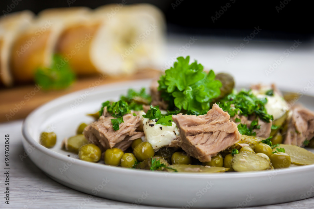 Tuna salad with cucumber, green peas, parsley and dill on the white plate Tuna salad with cucumber, green peas, parsley and dill on the white plate