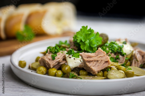 Tuna salad with cucumber, green peas, parsley and dill on the white plate