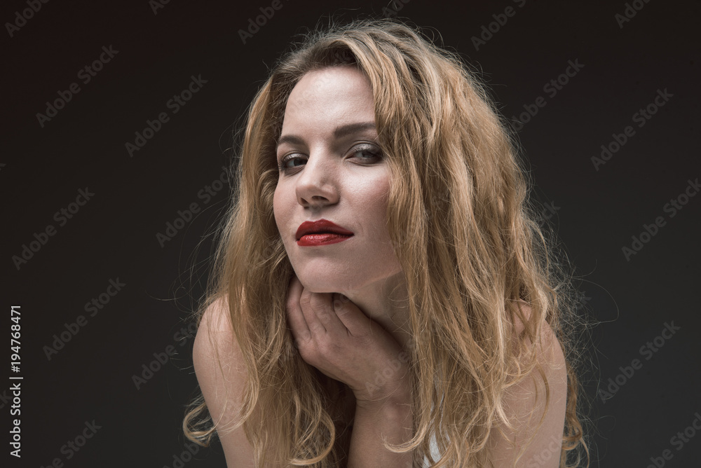 Fototapeta premium Portrait of attractive joyful woman with beautiful wavy hair looking at camera with mysterious smile. Isolated on background