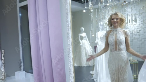  Close up portrait happy bride to be trying on her wedding gown in store. Young attractive bride in white beautiful wedding dress with flowers. Wedding concept. Wedding makeup and hairstyle.