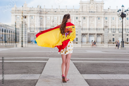 Young woman in front of Palacio de Oriente - the Royal Palace of Madrid, holding a flag 