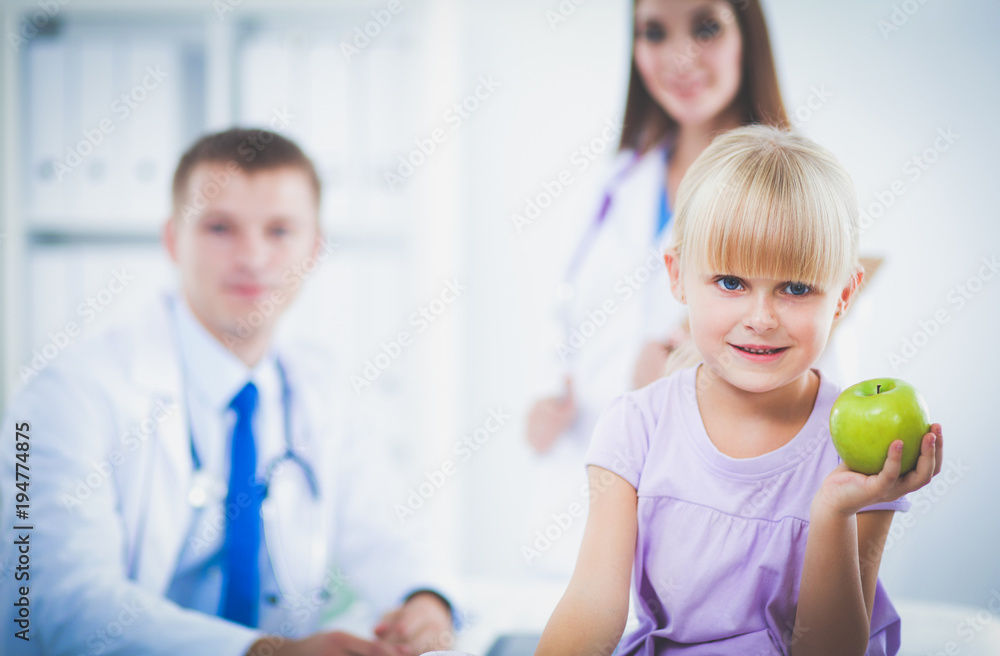 Obraz premium Child and medicine concept - female doctor giving an apple to little girl . Child and medicine concept