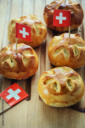 Celebrating Switzerland National Day on August 1st with traditional symbols like swiss flag red with white cross. Special bread buns with cross shape cut. Red berry sauce with  white cross.