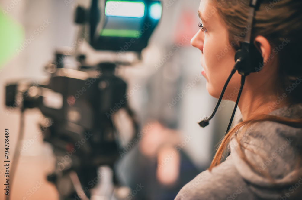 Fototapeta premium Behind the scene. Female cameraman shooting film scene with camera