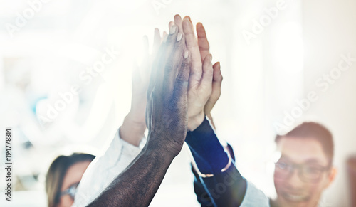 Team of diverse businesspeople high fiving together in an office