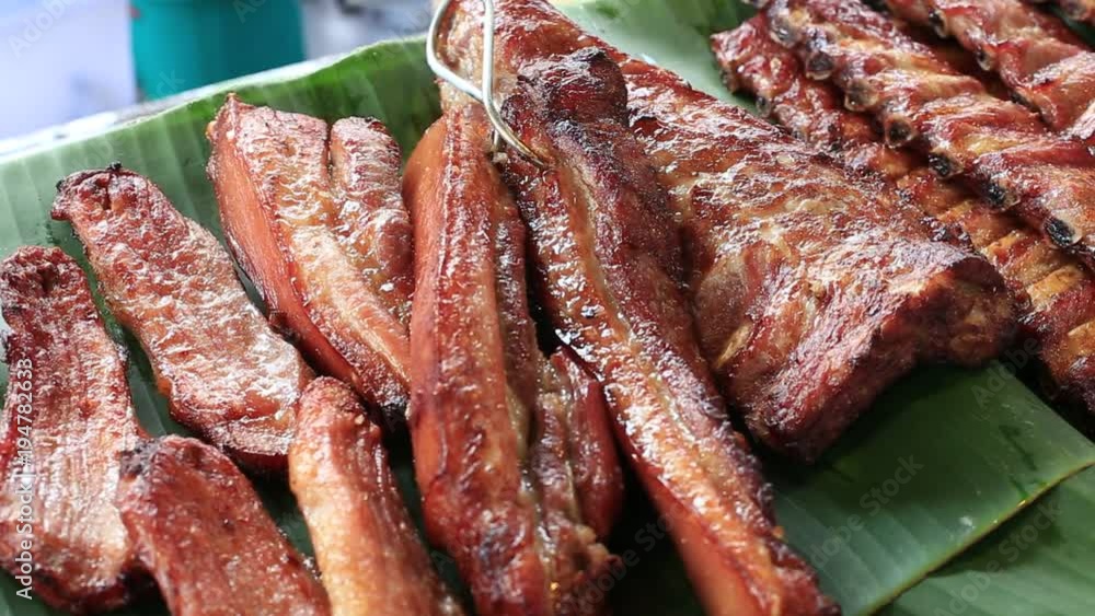 Street trade food : thai vendor prepares and sells smoked pork meat on the night food market in island Koh Phangan, Thailand. Close up Street trade food : thai vendor prepares and sells smoked pork meat on the night food market in island Koh Phangan, Thailand. Close up
