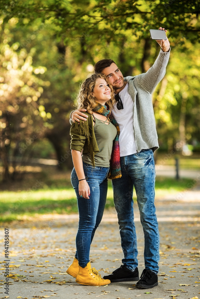 The young couple takes pictures by telephone in the park The young couple takes pictures by telephone in the park