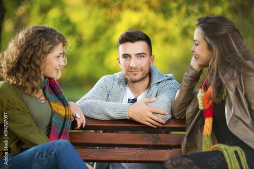 Three young people in a park on a bench