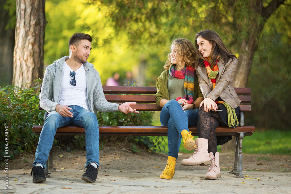 Three young people on a bench in a park