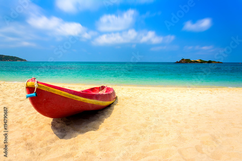 Red boat on the beach with blue sea and blue sky background