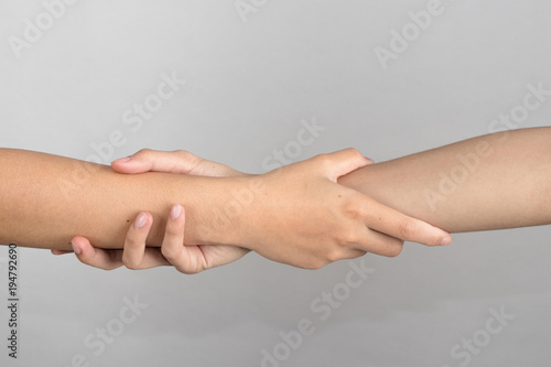 Rescuing and helping by holding or gripping the forearm.Hand and arm pulling up. The Concept of help, love, friendship, support, teamwork, partnership, reaching, couple.
