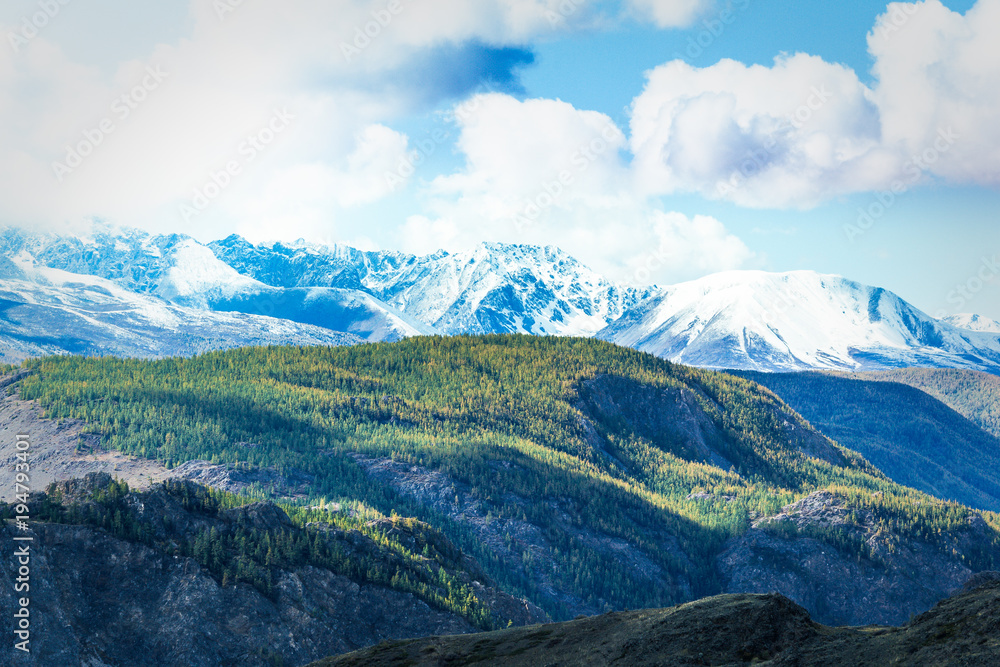 Mountain range with snow-covered peaks under the clouds. Landscape of mountain valleys and cliffs. Mountain range with snow-covered peaks under the clouds. Landscape of mountain valleys and cliffs.
