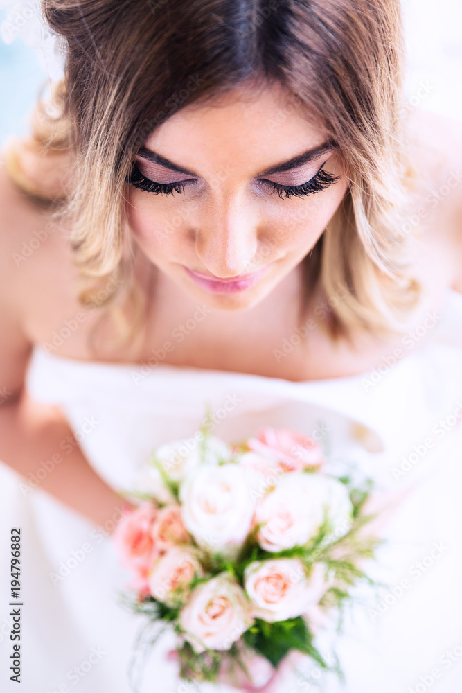 Romantic wedding moments. Portrait of a beautiful young bride holding flower bouquet. Top view. Romantic wedding moments. Portrait of a beautiful young bride holding flower bouquet. Top view.
