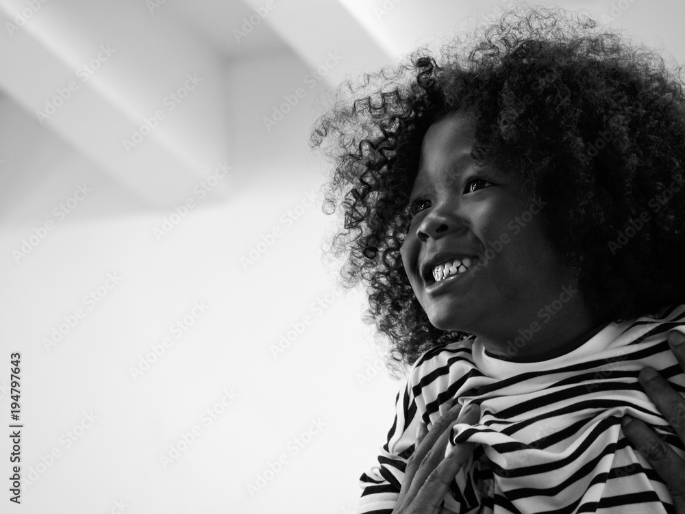 Obraz premium Black and white image of cute curly hair boy happy and having big smile when was push up high