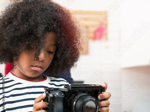 Cute curly hair boy interesting and playing with camera © Mongkolchon