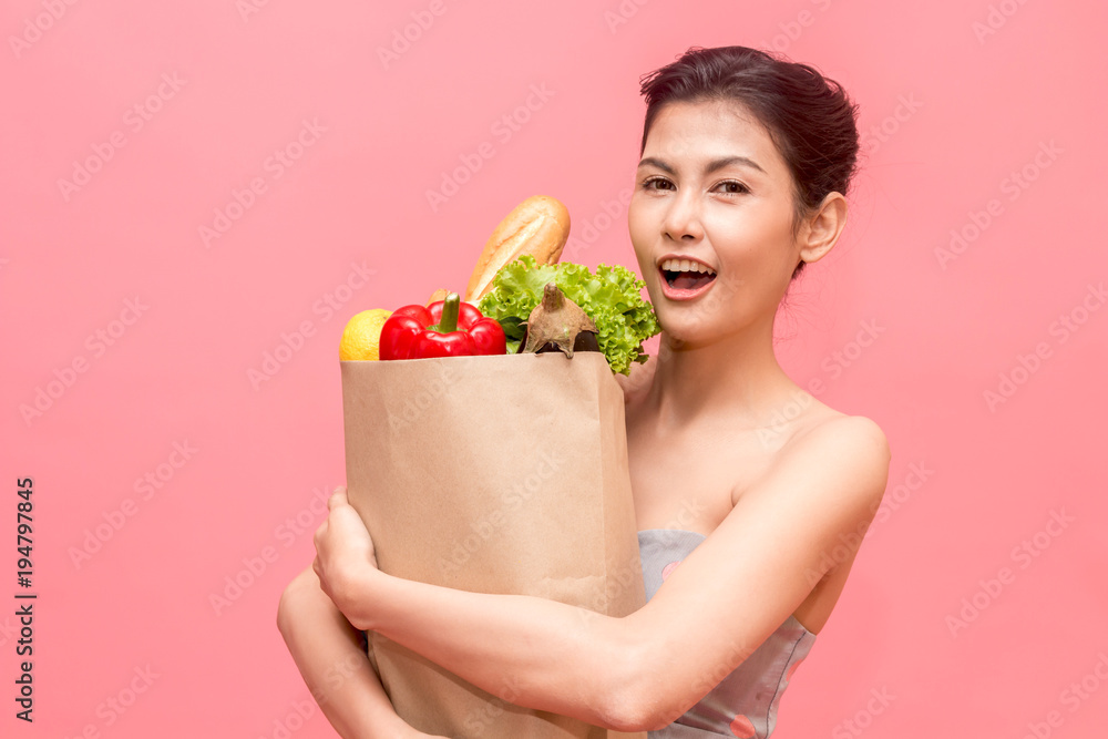 Woman holding shopping paper bag with fruit and vegetables diet healthy eating on pink background Woman holding shopping paper bag with fruit and vegetables diet healthy eating on pink background