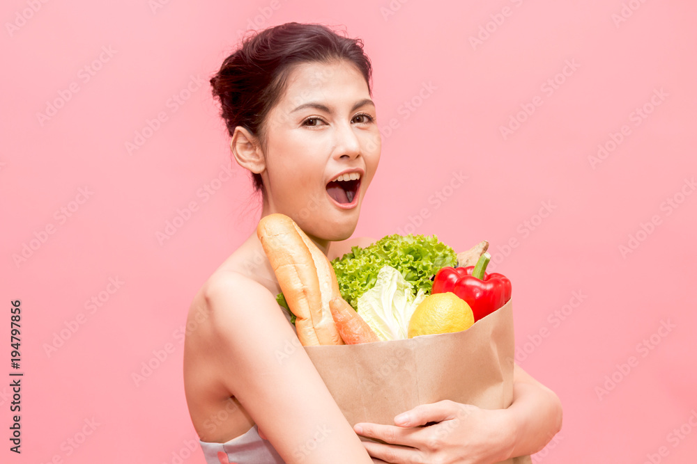 Woman holding shopping paper bag with fruit and vegetables diet healthy eating on pink background Woman holding shopping paper bag with fruit and vegetables diet healthy eating on pink background