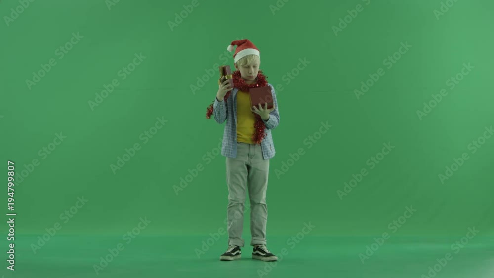 Boy looks inside his Christmas present, green chroma key background Boy looks inside his Christmas present, green chroma key background