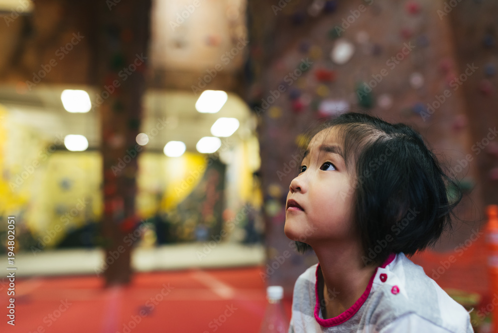 Girl observing activity at indoor rock climbing gym Girl observing activity at indoor rock climbing gym
