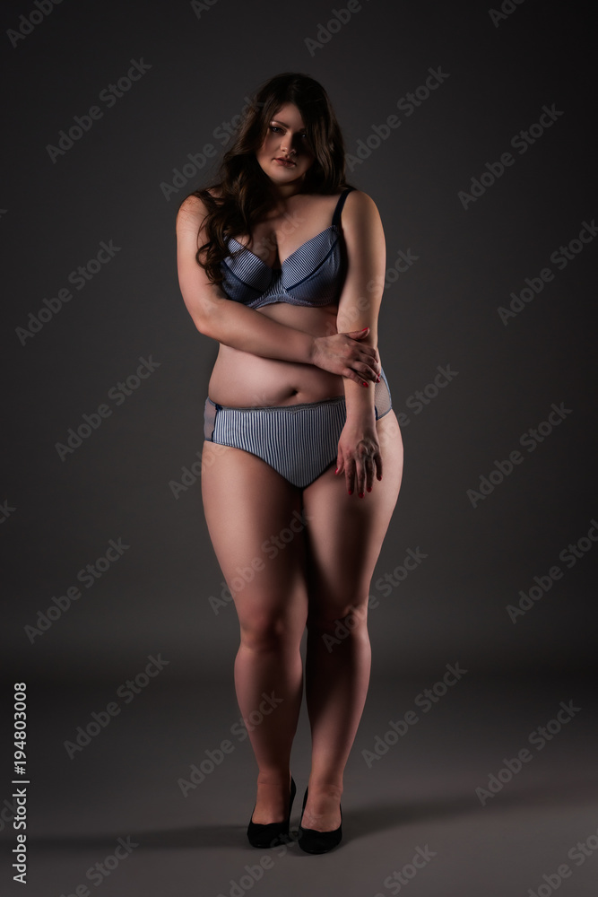 Plus size sexy model in underwear, fat woman on gray background, overweight female body