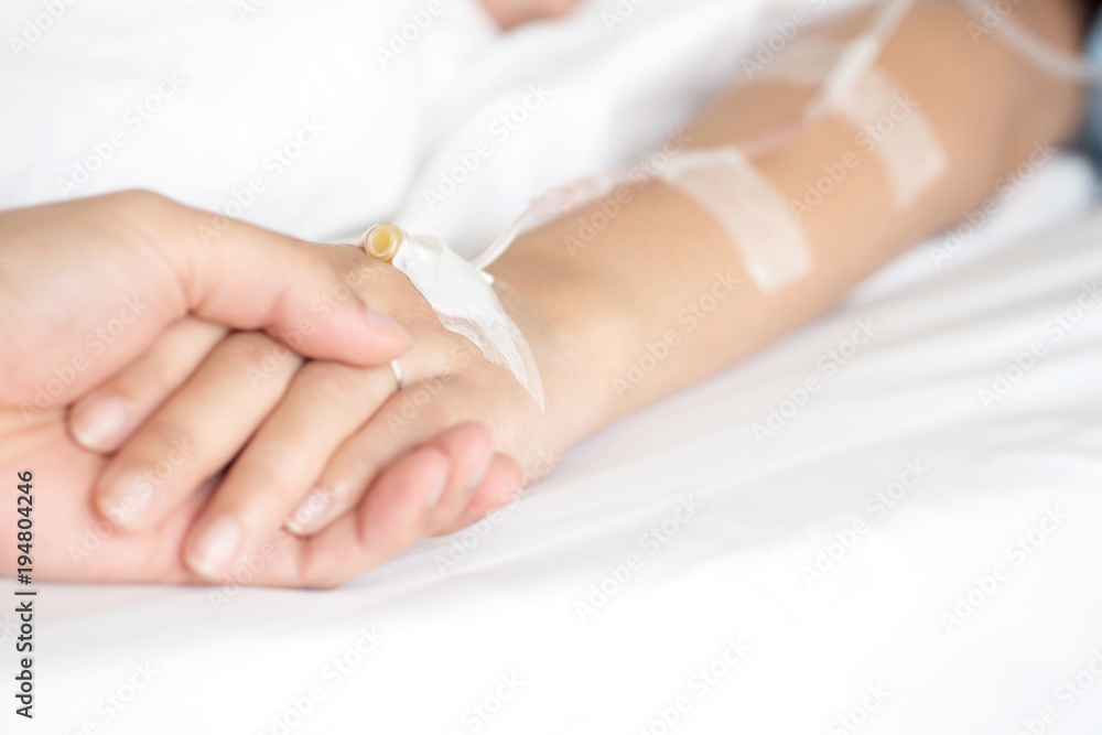 Man hand holding woman patient's hand on bed in hospital for reassuring and encouragement. Man hand holding woman patient's hand on bed in hospital for reassuring and encouragement.