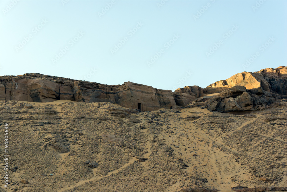 Sand dune and sandstone of the Sahara desert, near Cairo in Egypt with ruins of the entrance of an Egyptian tomb carved into the mountain